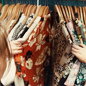 femme qui regarde des vêtements sur des cintres