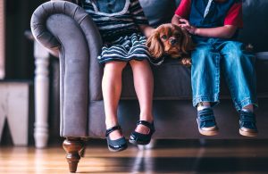 deux enfants assis sur un canapé avec un chien couché entre eux