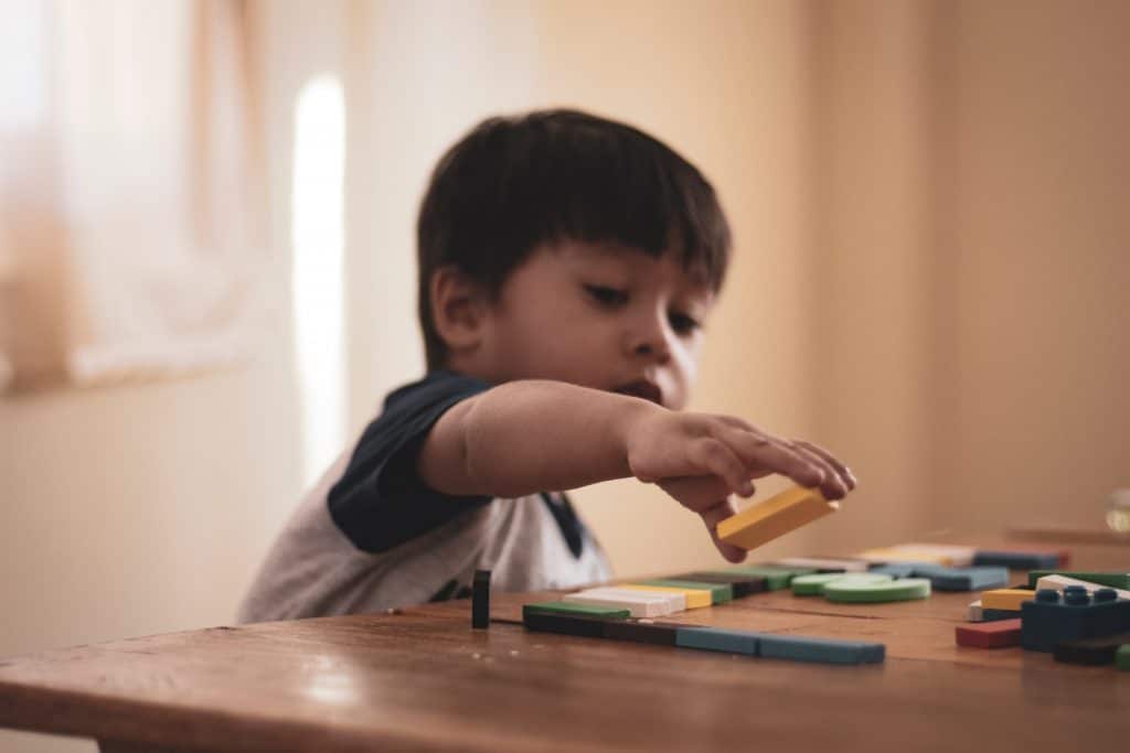 petit garçon qui joue avec un puzzle en bois offert en cadeau de Pâques